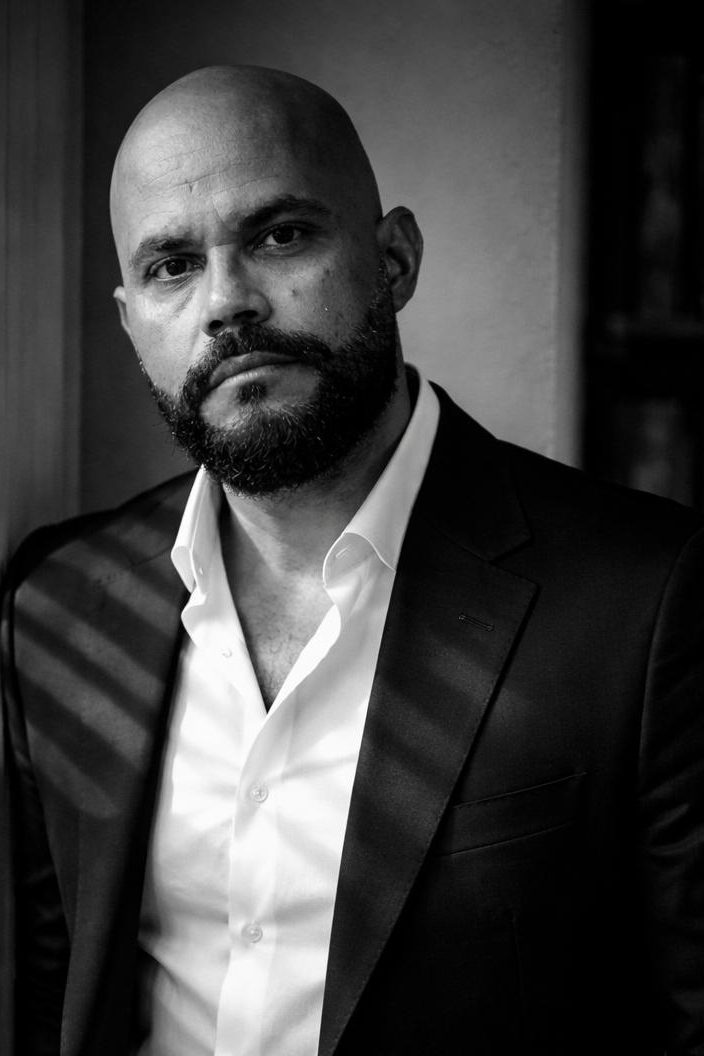 Retrato en blanco y negro de un hombre calvo con barba, vistiendo un traje oscuro y una camisa blanca, mirando a la cámara con expresión seria.